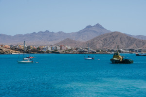 Sailing boats in the ocean against the backdrop of the city of Mindelo and its mountains on the island of Sao Vicente in Cape Verde.