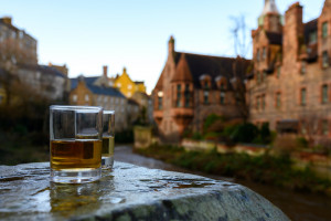 Scotch single malts or blended whisky spirits in glasses with old houses of Edinburgh city on background, Scotland, UK